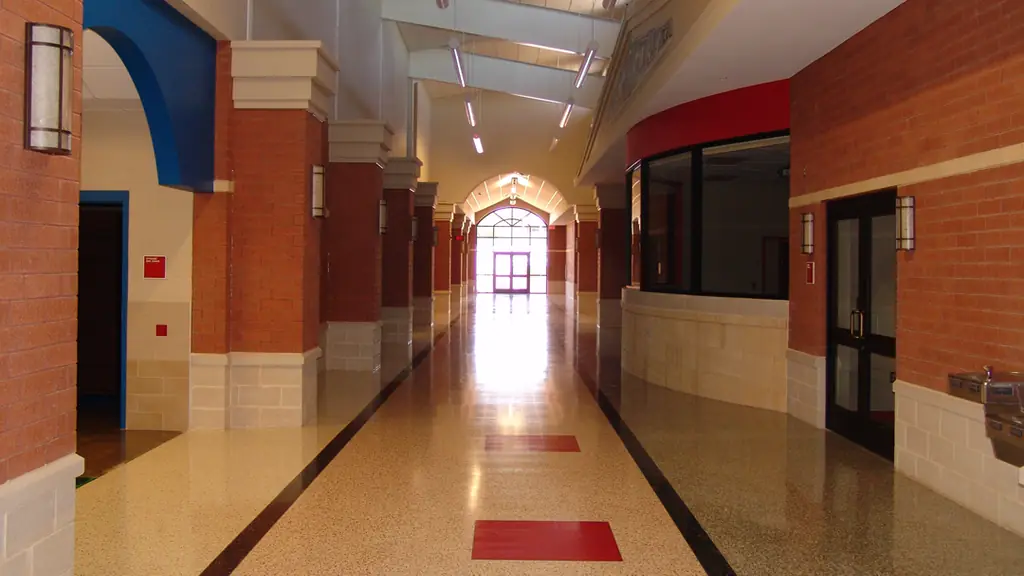 A school corridor in East Texas with freshly painted block walls above a brick base and a terrazzo floor